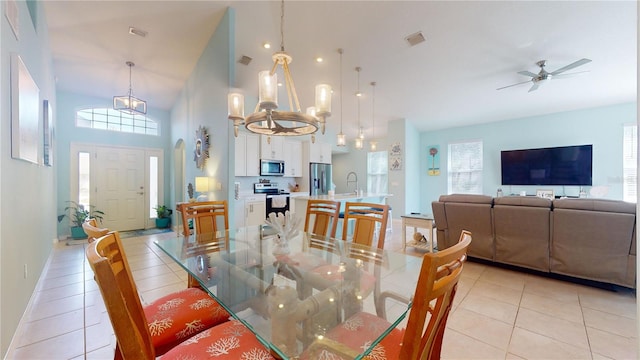 dining space featuring a wealth of natural light, ceiling fan with notable chandelier, light tile patterned floors, and high vaulted ceiling