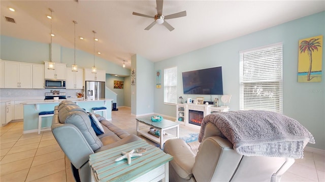 living room featuring vaulted ceiling, light tile patterned floors, and ceiling fan