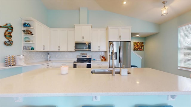 kitchen with stainless steel appliances, white cabinets, a kitchen bar, decorative backsplash, and vaulted ceiling