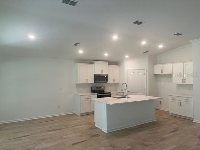 kitchen featuring stainless steel appliances, a kitchen island with sink, sink, and white cabinets