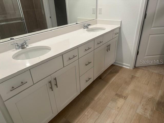 bathroom with vanity, hardwood / wood-style flooring, and a shower with shower door