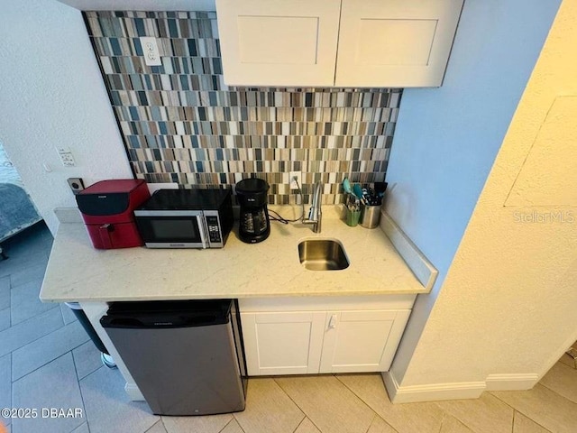 kitchen with white cabinetry, sink, backsplash, stainless steel appliances, and light stone counters