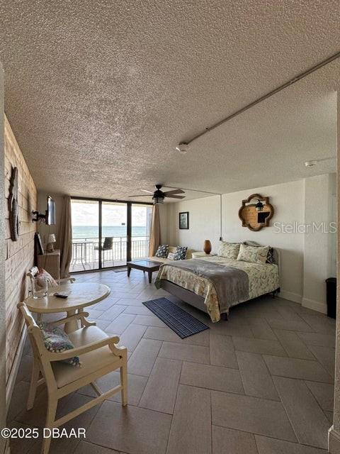 bedroom with access to exterior, a textured ceiling, a wall of windows, and a water view