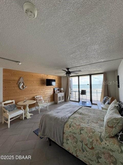 bedroom with wood walls, ceiling fan, and access to outside