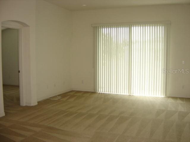 carpeted empty room featuring arched walkways