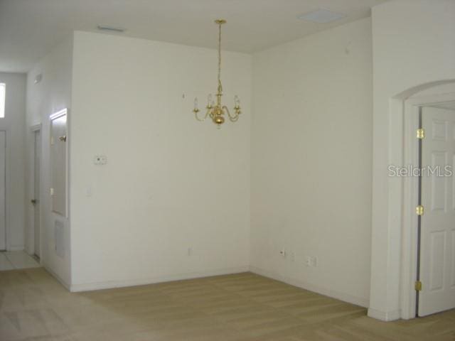 unfurnished dining area with baseboards, a notable chandelier, and light wood finished floors