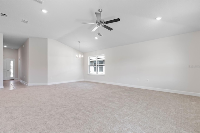 empty room with vaulted ceiling, ceiling fan with notable chandelier, and light colored carpet