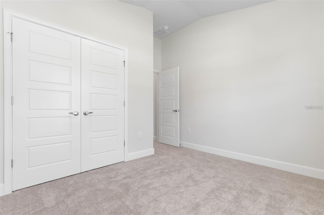 unfurnished bedroom with a closet, vaulted ceiling, and light colored carpet