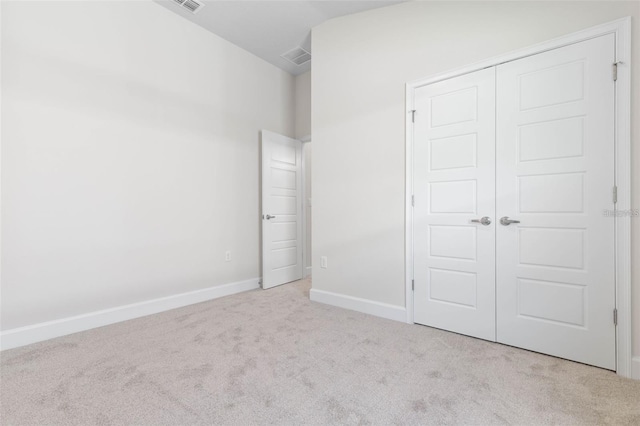 unfurnished bedroom with a closet, light colored carpet, and lofted ceiling