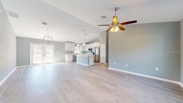 unfurnished living room with high vaulted ceiling, ceiling fan with notable chandelier, and light hardwood / wood-style floors