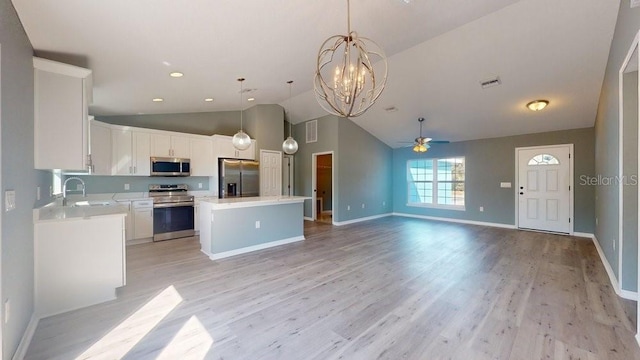 kitchen with pendant lighting, appliances with stainless steel finishes, a center island, white cabinets, and light wood-type flooring