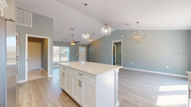 kitchen featuring hanging light fixtures, light wood-type flooring, stainless steel fridge, a kitchen island, and white cabinets