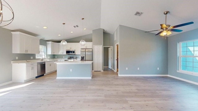 kitchen featuring sink, white cabinetry, a center island, hanging light fixtures, and stainless steel appliances