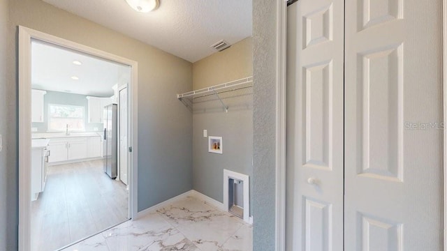 clothes washing area with washer hookup, sink, and a textured ceiling