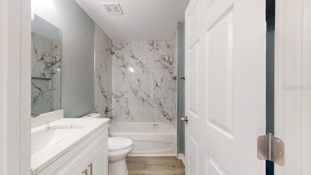 full bathroom featuring hardwood / wood-style floors, tiled shower / bath combo, vanity, toilet, and a textured ceiling