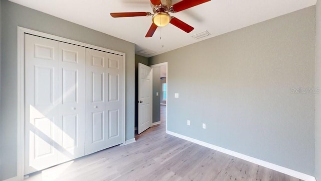 unfurnished bedroom with ceiling fan, a closet, and light wood-type flooring