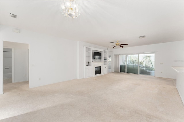 unfurnished living room with ceiling fan with notable chandelier, built in features, and light colored carpet