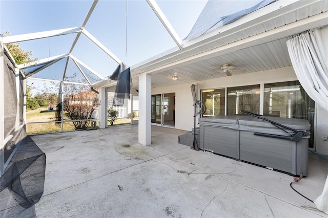 view of patio featuring a hot tub, ceiling fan, and glass enclosure