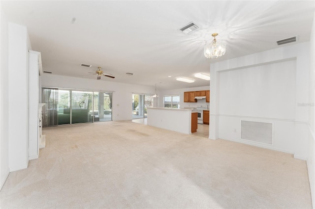 unfurnished living room with ceiling fan with notable chandelier and light carpet