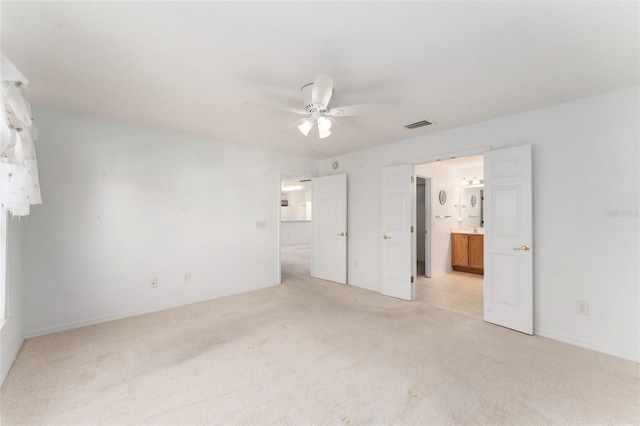 unfurnished bedroom featuring connected bathroom, light carpet, and ceiling fan