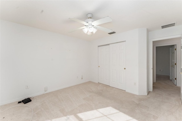 unfurnished bedroom featuring ceiling fan, a closet, and light carpet