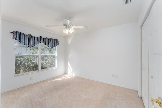 empty room featuring ceiling fan and light carpet