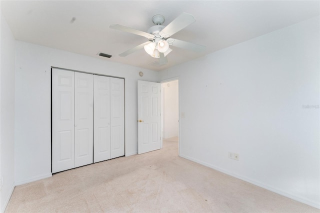 unfurnished bedroom featuring light colored carpet, ceiling fan, and a closet