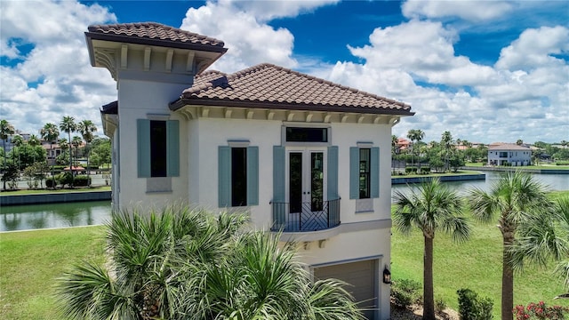 view of side of property with a garage, a water view, and a yard