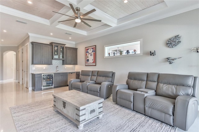 living room with beamed ceiling, beverage cooler, ornamental molding, coffered ceiling, and wet bar