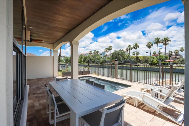 view of patio / terrace with a swimming pool, ceiling fan, and a water view