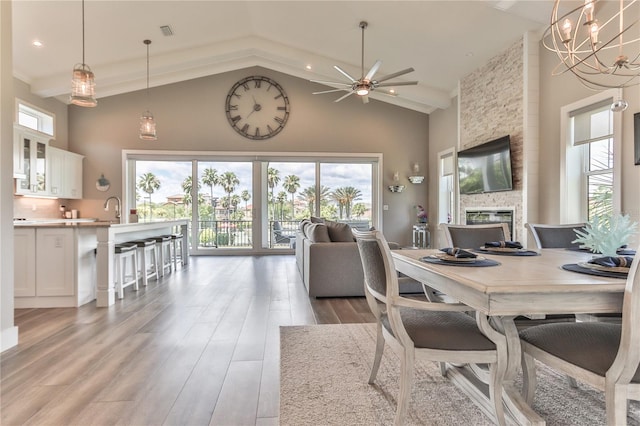 dining space with hardwood / wood-style flooring, a stone fireplace, a healthy amount of sunlight, and a towering ceiling