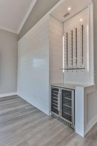 bar with wine cooler, crown molding, and light hardwood / wood-style floors