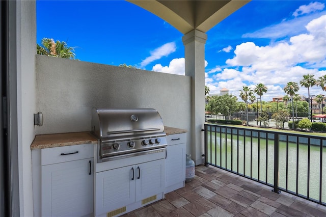 view of patio / terrace with a water view, an outdoor kitchen, and a grill