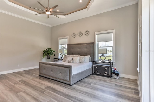 bedroom with crown molding, ceiling fan, a raised ceiling, and light hardwood / wood-style flooring