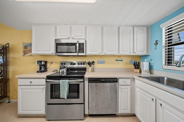 kitchen with white cabinetry, appliances with stainless steel finishes, sink, and light tile patterned floors