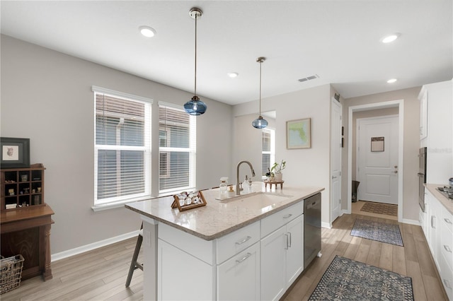 kitchen with sink, pendant lighting, light stone countertops, a kitchen island with sink, and white cabinets