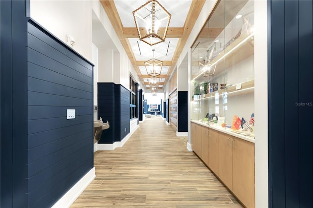 corridor featuring light wood-type flooring and an inviting chandelier