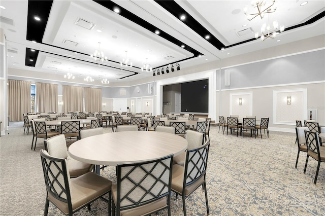 dining space with a towering ceiling, a tray ceiling, and a notable chandelier