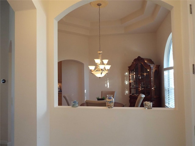 unfurnished dining area featuring a chandelier and a tray ceiling