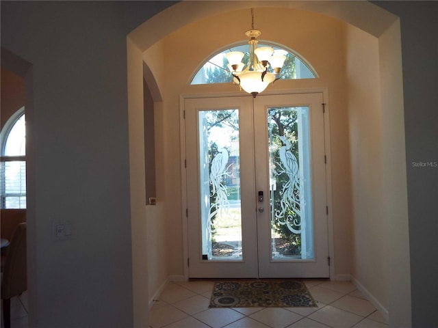 interior space featuring an inviting chandelier, light tile patterned floors, baseboards, and french doors