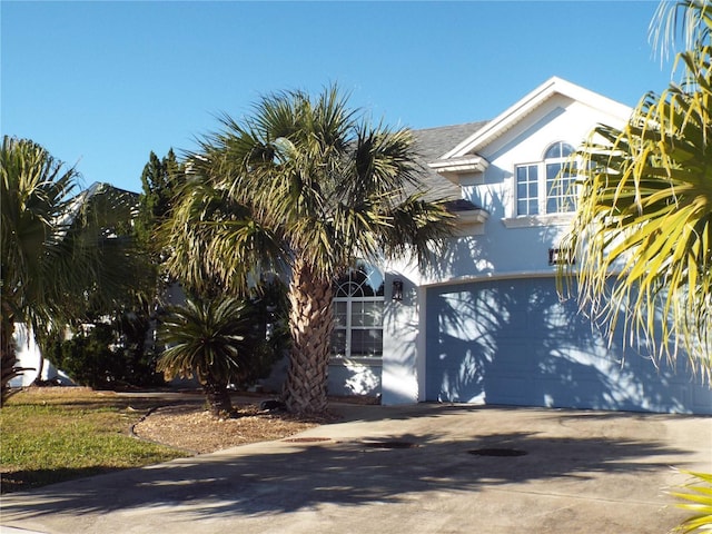 view of side of property featuring driveway, an attached garage, and stucco siding