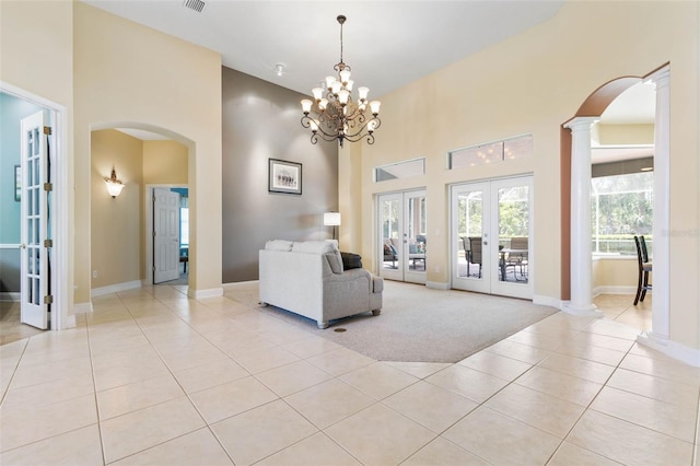 unfurnished living room featuring decorative columns, a high ceiling, light tile patterned floors, and french doors