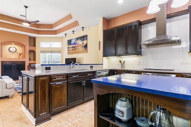 kitchen featuring light tile patterned floors, wall chimney range hood, backsplash, dark brown cabinetry, and black gas stovetop