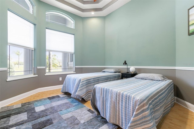 bedroom with wood-type flooring and a raised ceiling