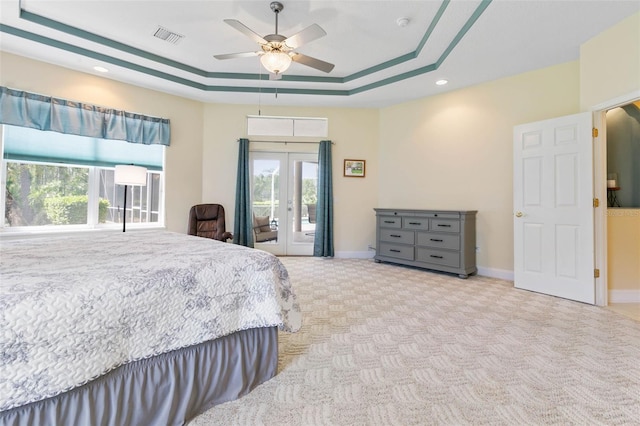 bedroom featuring ceiling fan, access to exterior, a tray ceiling, light colored carpet, and french doors