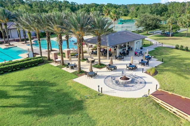 view of community featuring a fire pit, a swimming pool, a patio area, and a lawn