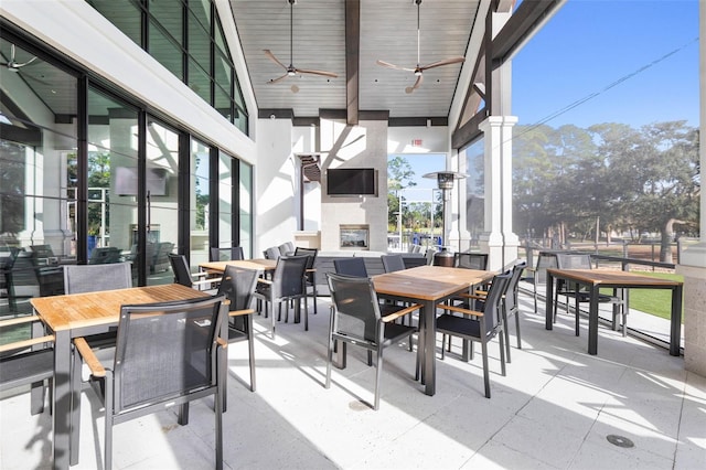 view of patio featuring ceiling fan and a large fireplace