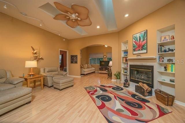 living room featuring ceiling fan, built in features, and light hardwood / wood-style flooring