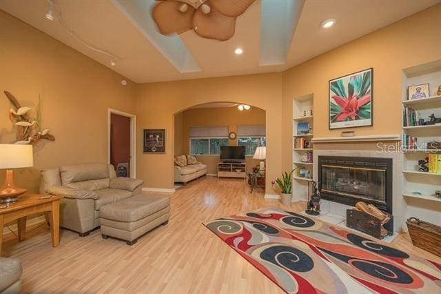 living room with a fireplace, wood-type flooring, and built in features