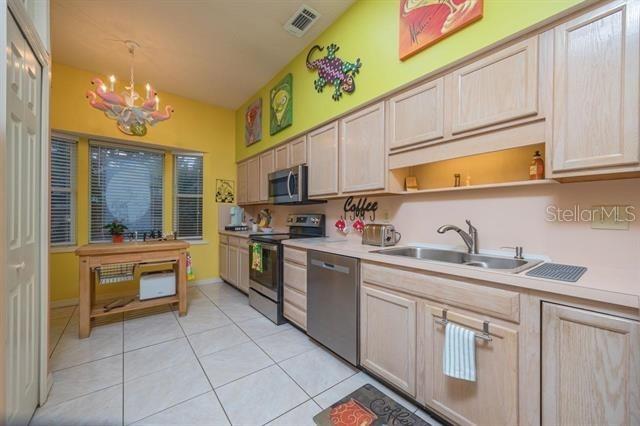 kitchen featuring sink, hanging light fixtures, stainless steel appliances, light tile patterned flooring, and light brown cabinetry